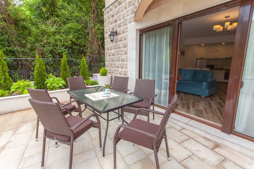 Terrace with wicker furniture and a view of the garden in an apartment, Kamenovo, Montenegro. Exit from the living room with kitchen.
