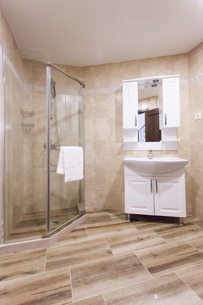 Bathroom in an apartment in Kamenovo, Montenegro: shower cabin, white vanity with sink, and beige tiles.