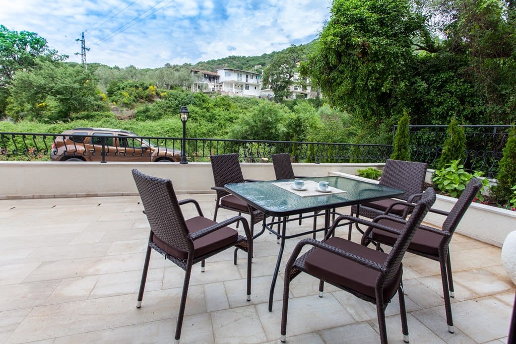 Cozy terrace with wicker furniture and mountain views in an apartment in Kamenovo, Montenegro. Spacious tiled balcony.