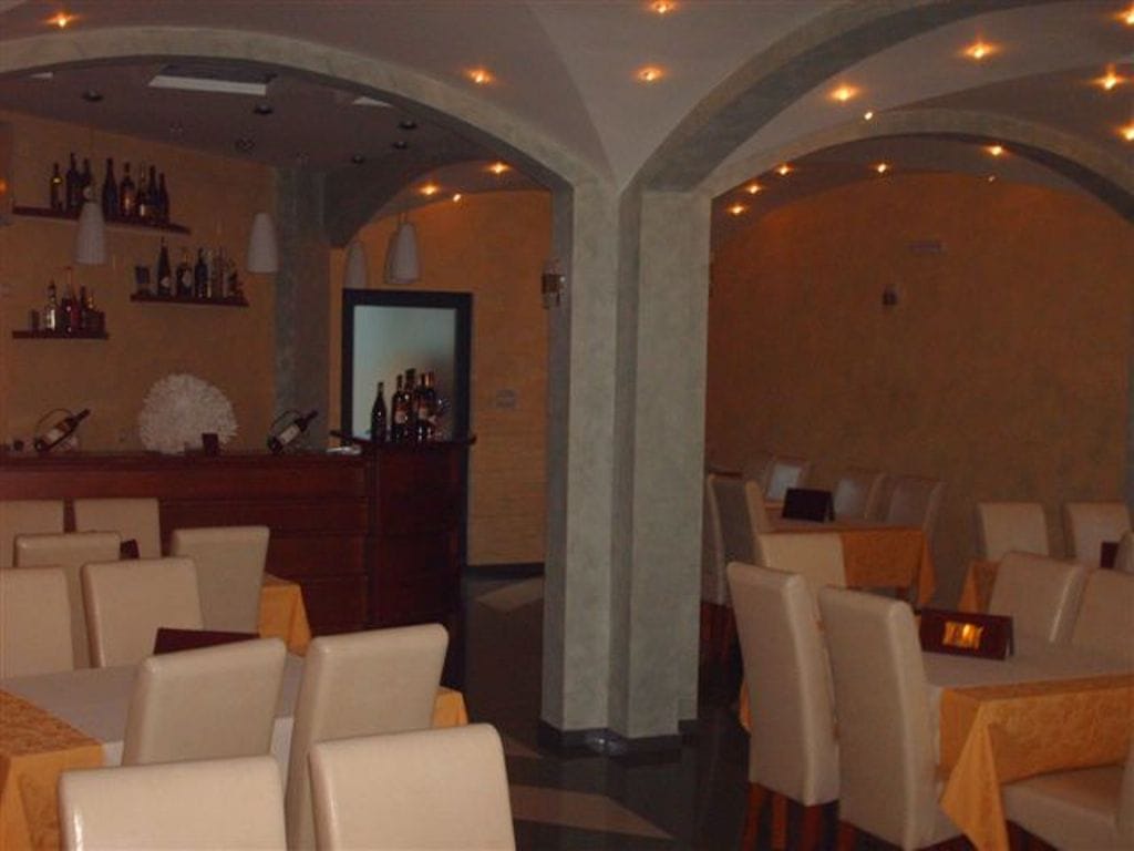 Interior of the mini-hotel restaurant in Bijela, Montenegro: arched vaults, a bar counter, dining tables, and light-colored furniture.