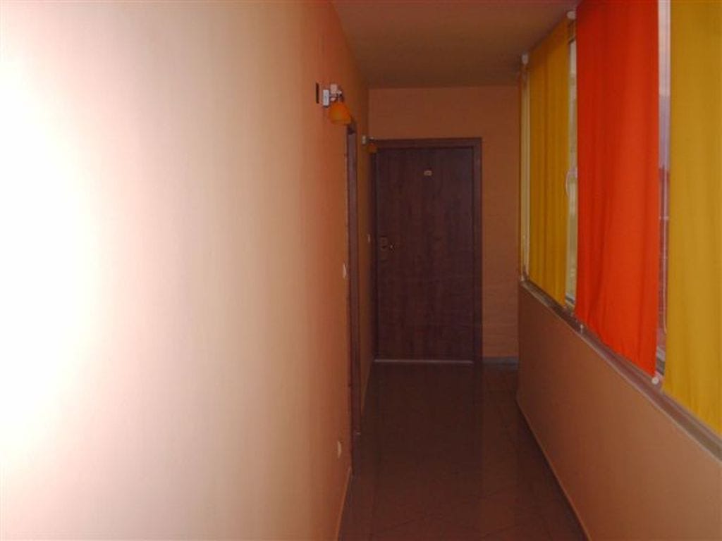 Long covered balcony with orange curtains in a mini-hotel, Bijela, Montenegro. View of the corridor and entrance door.