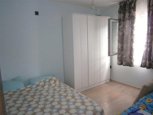Bedroom in a villa in Sutomore, Montenegro: a bright room with a double bed, a white wardrobe, and a window with curtains.