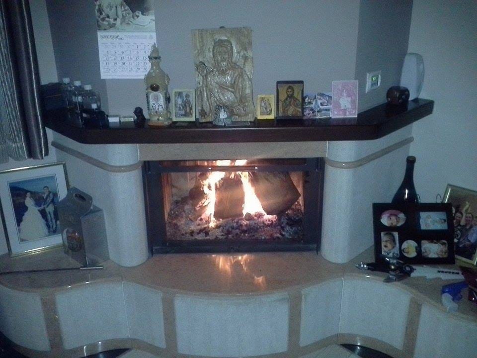 Cozy fireplace with a burning fire in the villa living room in Sutomore, Montenegro, with decor on the marble mantel.
