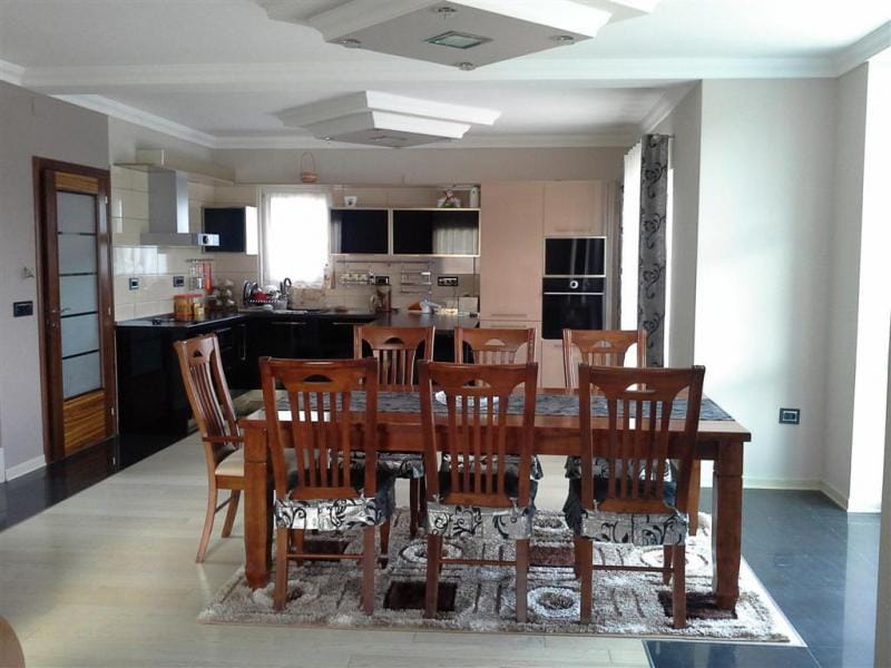 Modern kitchen-dining room with a wooden dining table in a villa in Sutomore, Montenegro. Interior with dark furniture.