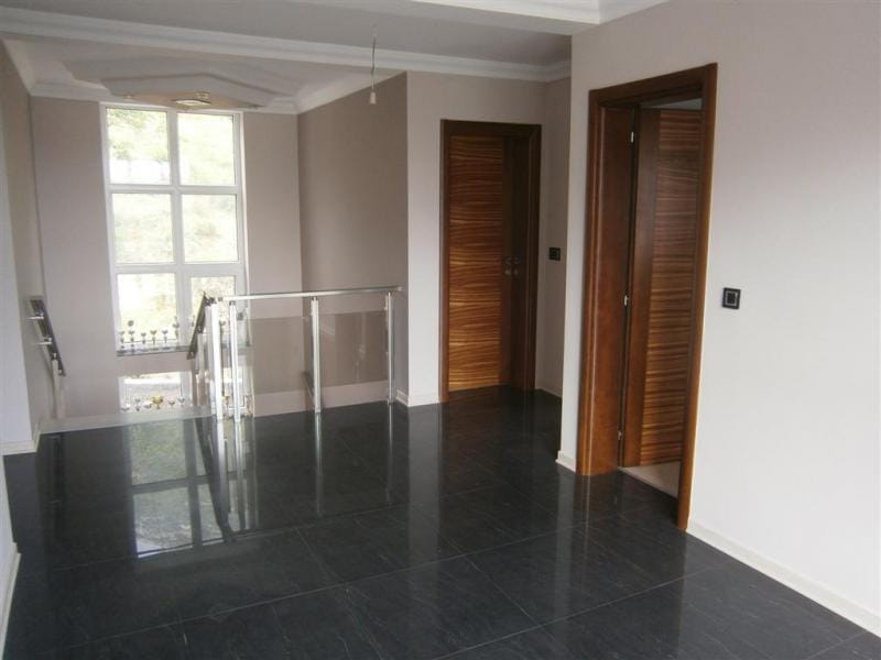 Villa interior in Sutomore, Montenegro: a modern hall with dark porcelain tile, glass railing, and doors.
