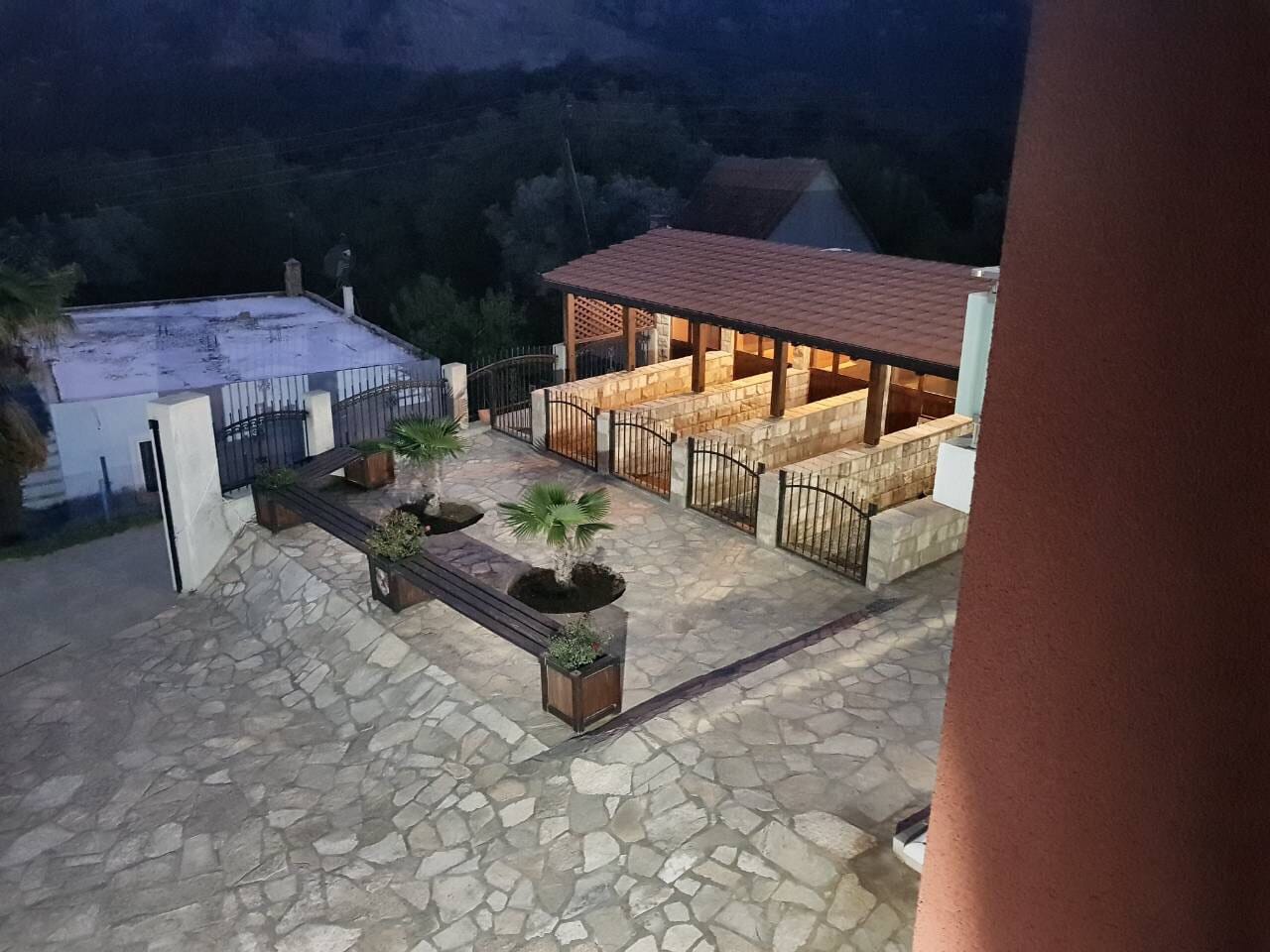 Evening view of the landscaped courtyard of a villa in Sutomore, Montenegro: stone terrace, gazebo, and landscape design.