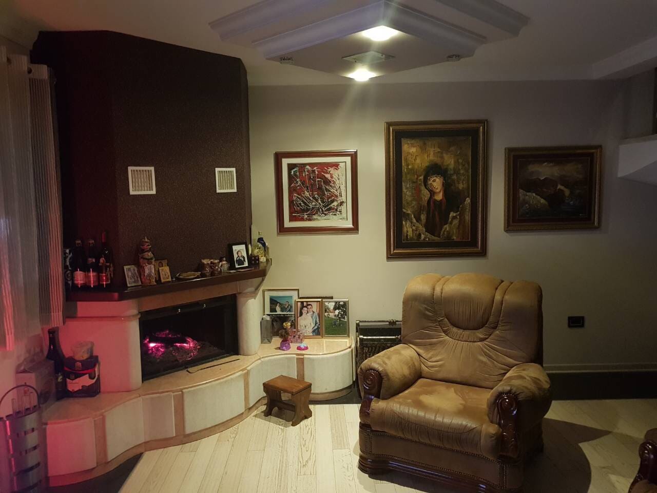 Cozy living room with a fireplace and leather armchair in a villa in Sutomore, Montenegro: classic interior with paintings.