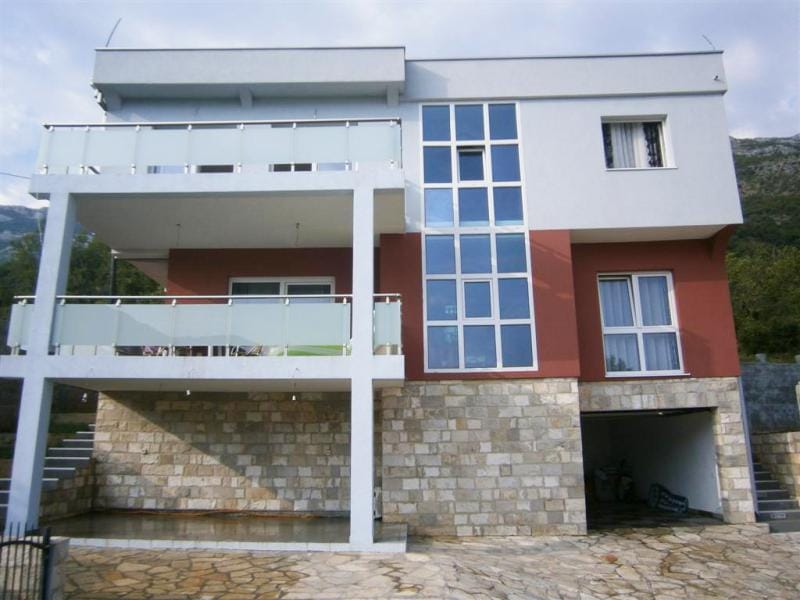 Modern villa in Sutomore, Montenegro: facade with panoramic glazing, stone cladding, and spacious balconies.