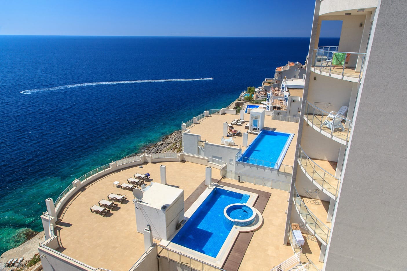 Apartments in Dobri Vody, Montenegro: view of the terrace with pools, a jacuzzi, and sun loungers by the Adriatic Sea.
