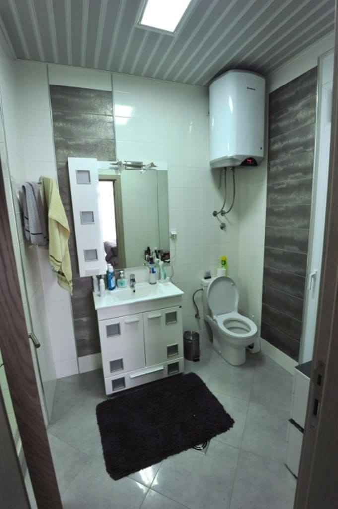 Bathroom in an apartment, Dobre Vode, Montenegro: white furniture, mirror, boiler, and modern tile finish.