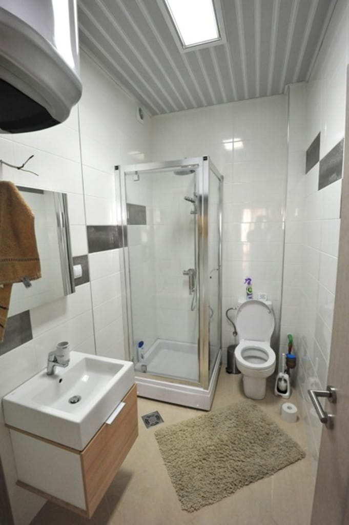 Modern bathroom with shower cabin in an apartment, Dobri Vody, Montenegro: white tiles, vanity with sink.