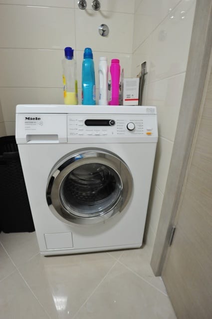 Miele washing machine in the apartment bathroom in Dobri Vody, Montenegro: light tiles and quality appliances.