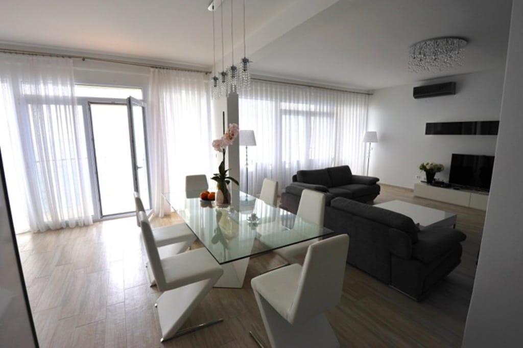 Bright living room with dining area and panoramic windows in an apartment, Dobri Vody, Montenegro. Modern interior.