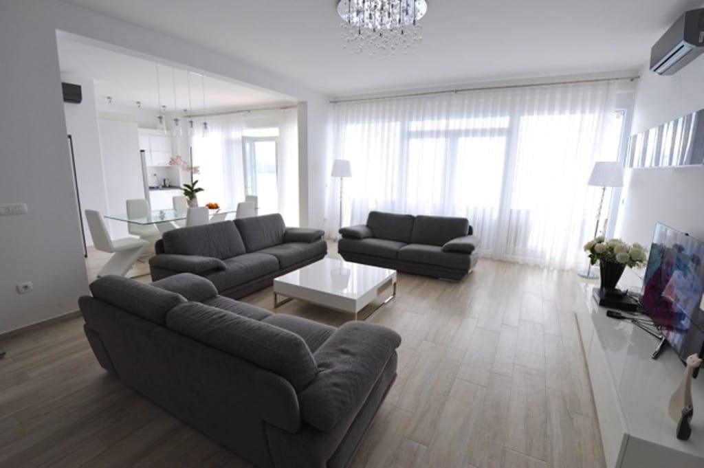 Modern living room with gray sofas in an apartment in Dobre Vode, Montenegro: bright interior and dining area.