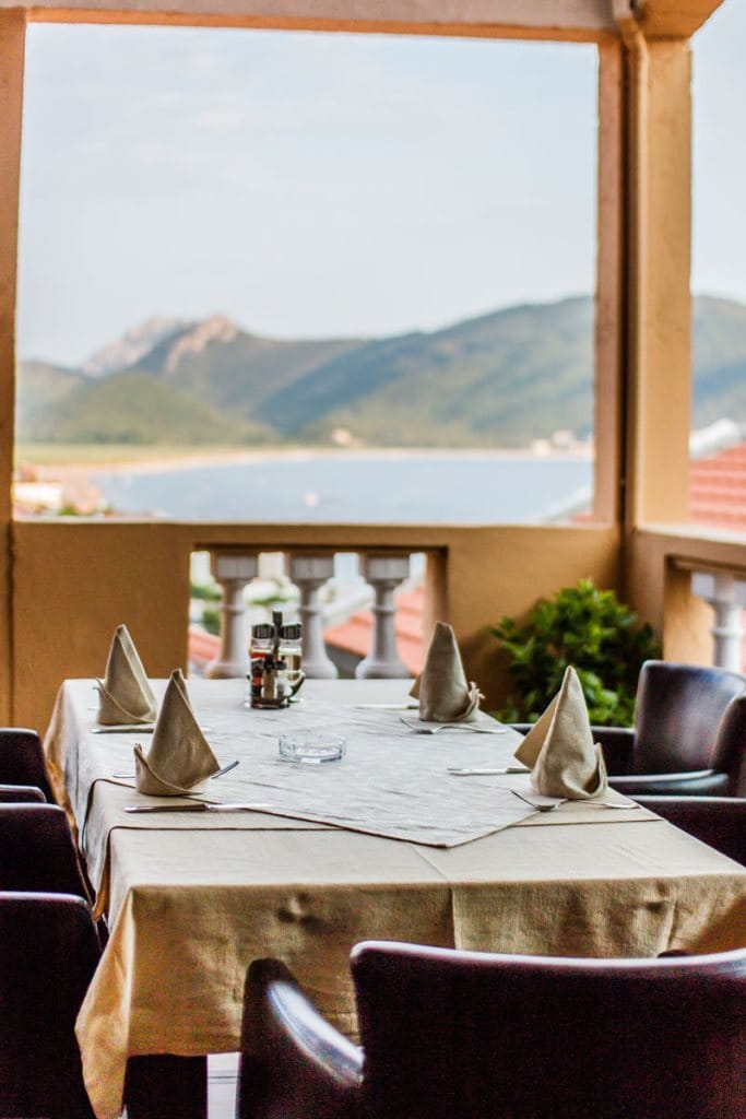 Set table on the hotel balcony in Buljarica, Montenegro, with panoramic sea and mountain views.