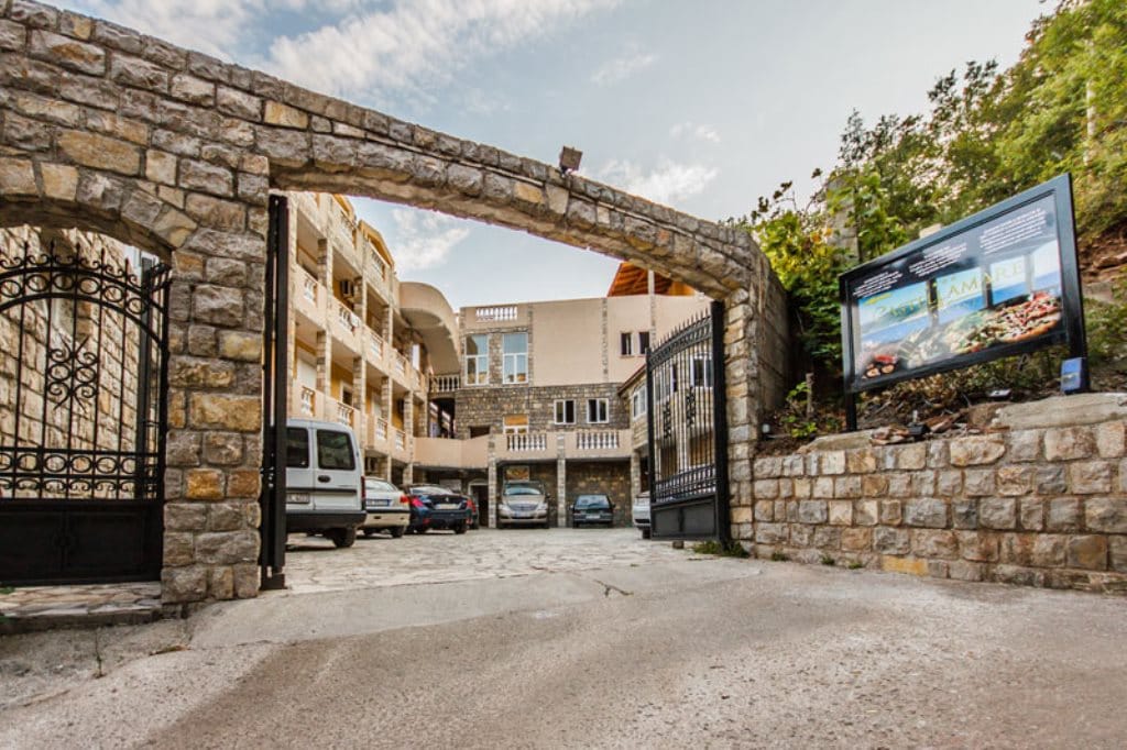 Entrance to Castellamare Hotel with a stone arch and parking, Buljarica, Montenegro: exterior view of the building facade.