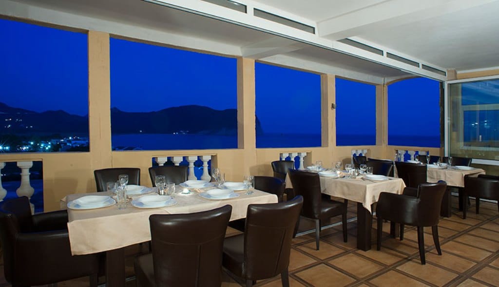 Hotel restaurant terrace in Buljarica, Montenegro: set tables, leather chairs, and a panoramic sea view.