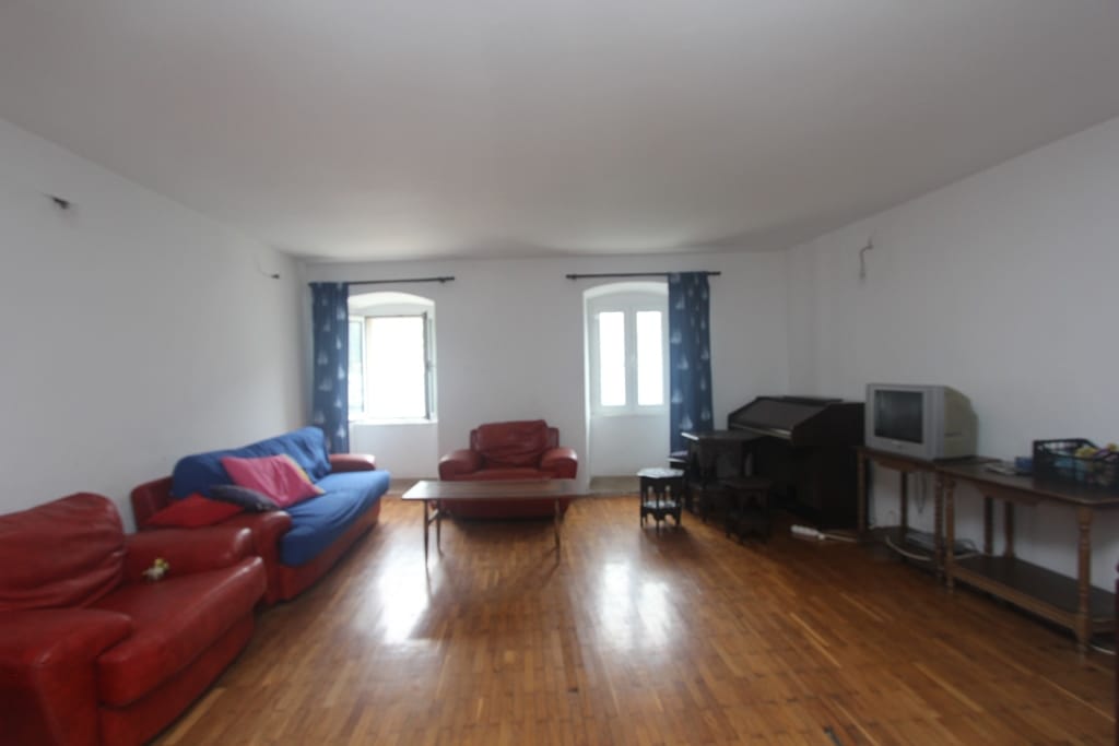 Spacious living room with parquet flooring, red leather armchairs, and a blue sofa in a house, Muo, Montenegro.