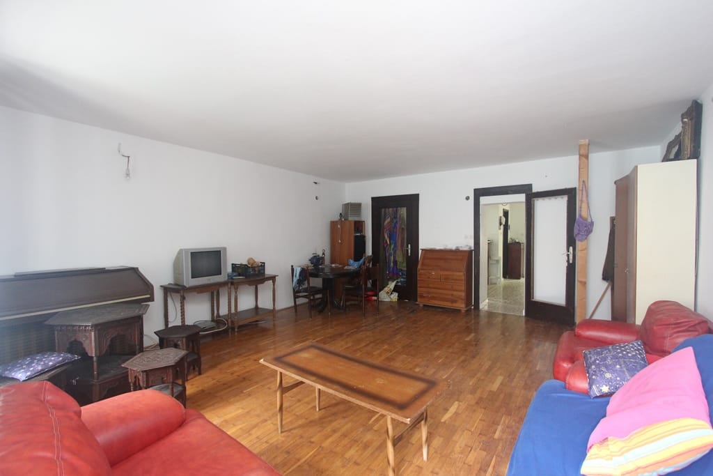 Spacious living room with wooden floors and furniture in a house for sale in Muo, Montenegro. View of the lounge and dining area.