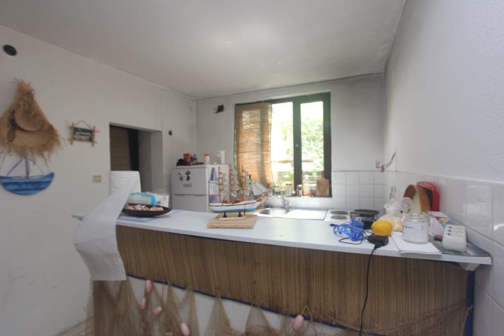 Kitchen with a breakfast bar in a house in Muo, Montenegro: bright interior, nautical decor, and a view of greenery from the window.