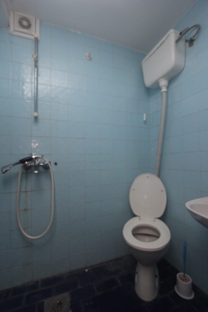 Bathroom with blue tiles and a shower in a house for sale in Muo, Montenegro. Compact bathroom with fixtures.