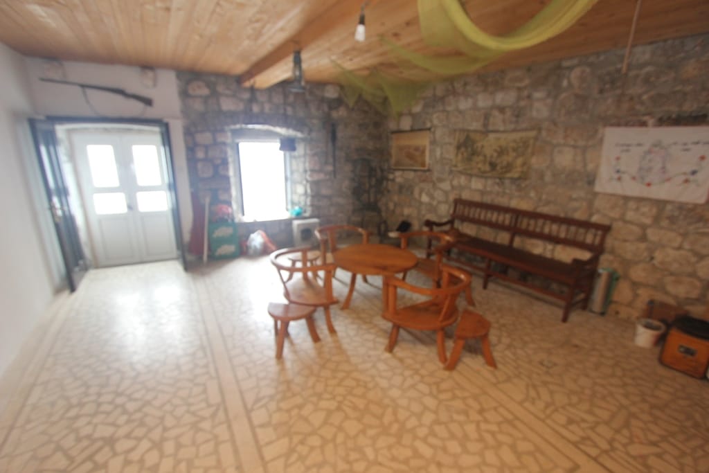 Living room in a stone house in Muo, Montenegro: wooden furniture, natural stone walls, and a wooden ceiling.