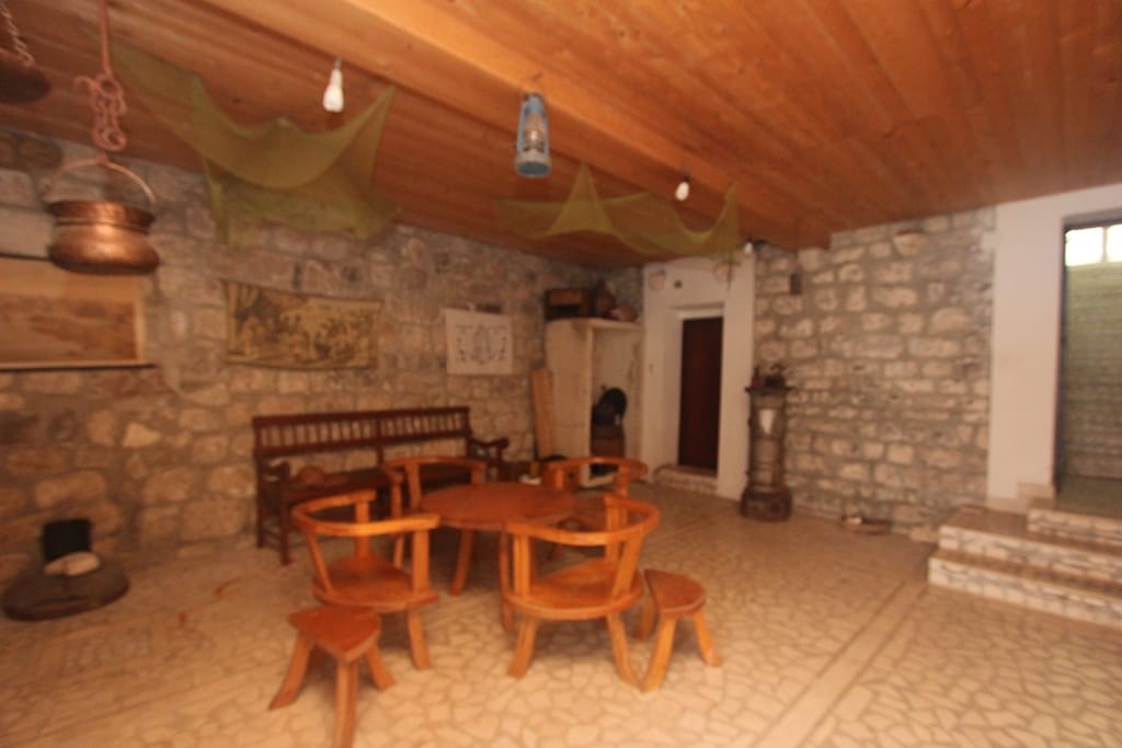 Rustic-style living room in a house in Muo, Montenegro: stone walls, wooden ceiling, and antique furniture.