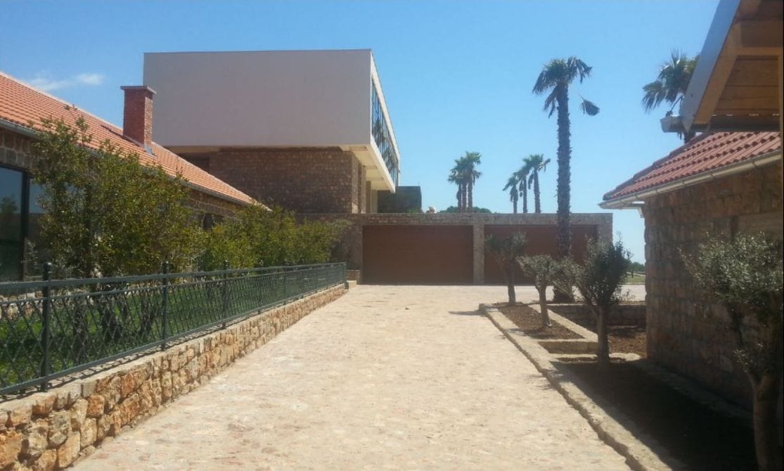 Modern villa in Krimovica, Montenegro: stone facade, two-car garage, and a garden with palm trees.