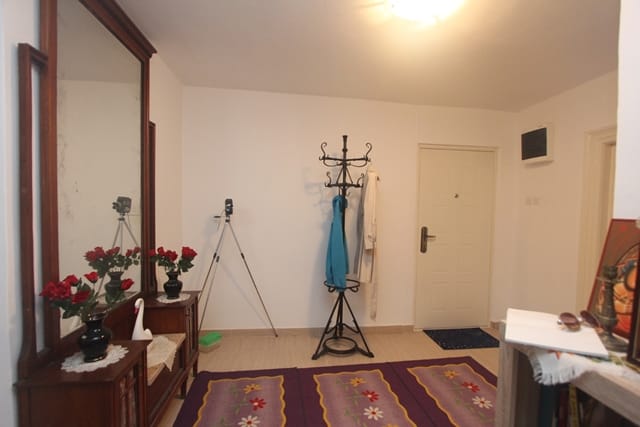 Hallway in a house in Muo, Montenegro: light walls, a vintage mirror with a cabinet, a standing coat rack, and a floral rug.