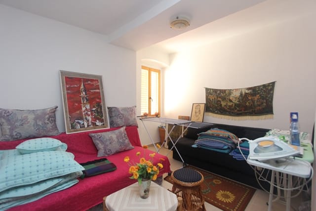 Living room in a house in Muo, Montenegro: two sofas, a coffee table, wall art decor, and a bright window with shutters.