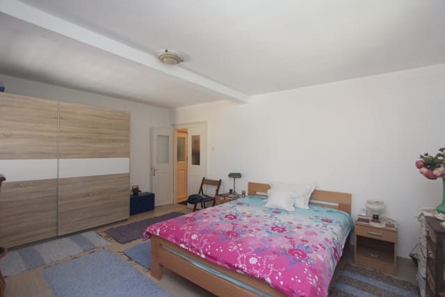 Bright bedroom with a double bed and a built-in wardrobe in a house in Muo, Montenegro. Cozy interior with white walls.