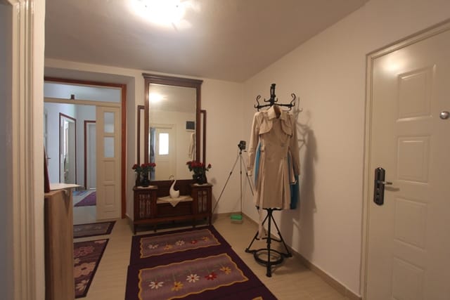 Hallway in a house in Muo, Montenegro: light walls, a vintage mirror with a console, a coat rack, and rugs on the floor.
