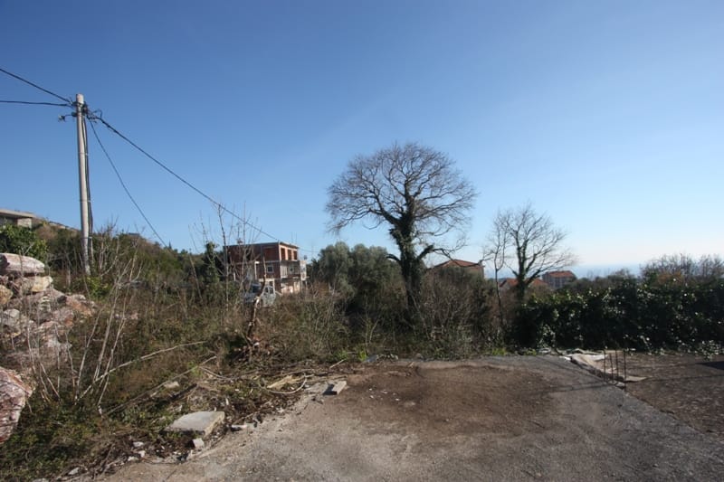 Building plot in Krimovica, Montenegro: view of the site with trees and a panoramic view of the surrounding area.