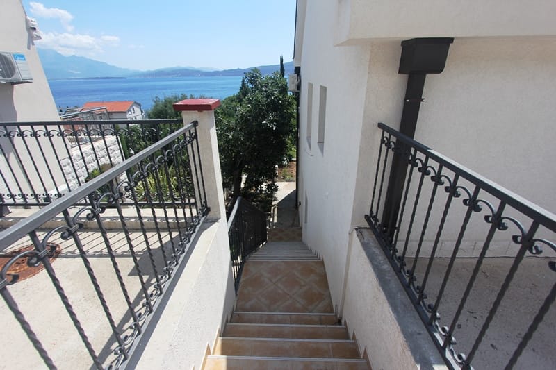Staircase with wrought-iron railings and sea view by the house in Baošići, Montenegro: terrace and tiled facade finish.