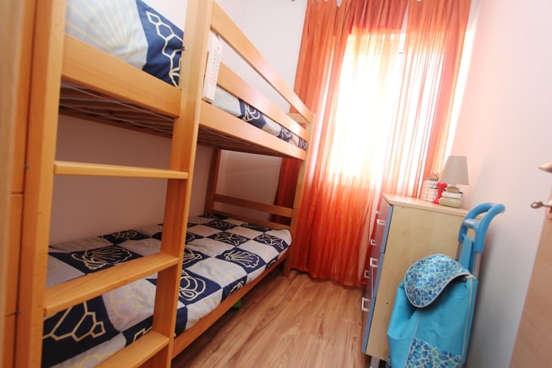 Children’s bedroom with a bunk bed in a house in Baošići, Montenegro: a bright room with a dresser and colorful curtains.