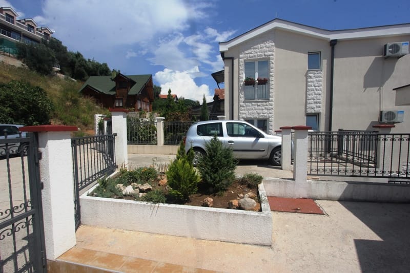 Two-story house with parking and landscaping in Baošići, Montenegro: view of the facade and surrounding grounds.