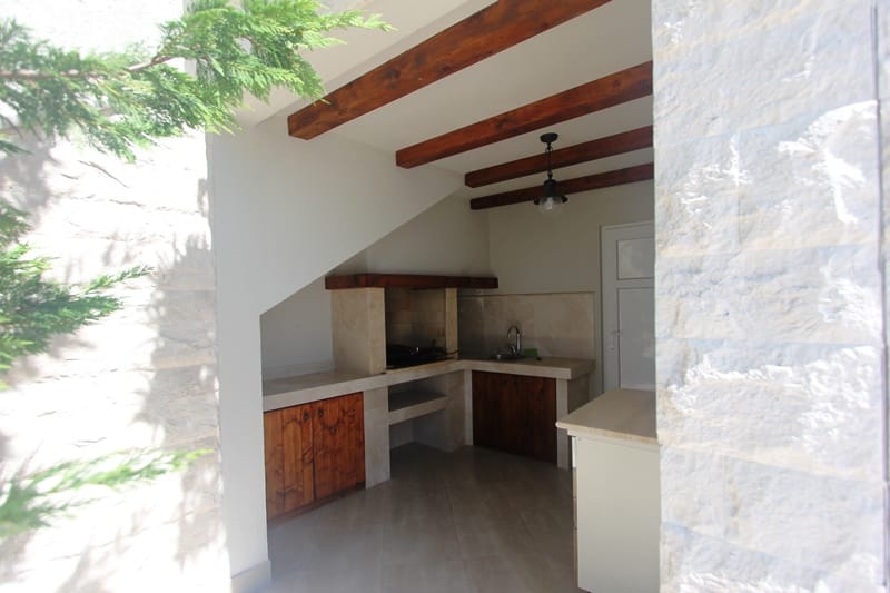 Summer kitchen with barbecue and wooden beams at a villa in Blizikuće, Montenegro: stone finish and cooking area.