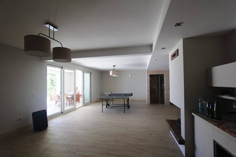 Spacious living room with a ping-pong table and access to the terrace in a villa in Blizikuće, Montenegro. Modern interior.