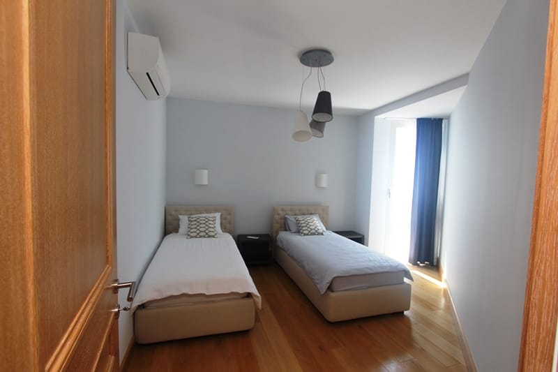 Bedroom with two beds, parquet flooring, and air conditioning in a villa in Blizikuće, Montenegro. Modern room interior.