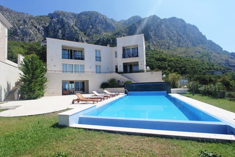Modern villa with a pool and terrace in Blizikuće, Montenegro, against a backdrop of picturesque mountain scenery.
