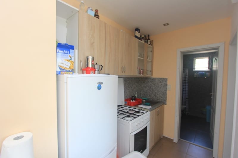 Compact kitchen with a white refrigerator and gas stove in a house, Seoc, Montenegro. View of the bathroom entrance.