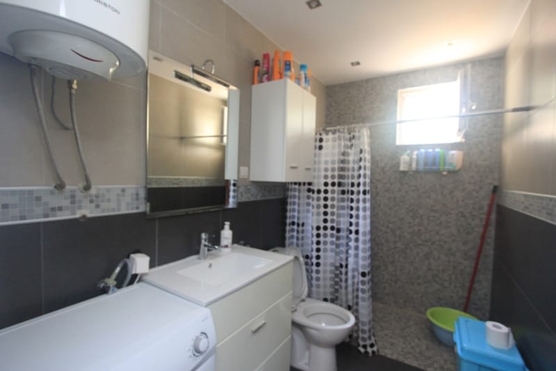 Modern bathroom with shower and washing machine in a house, Seoc, Montenegro. Tiled finish, bright interior.