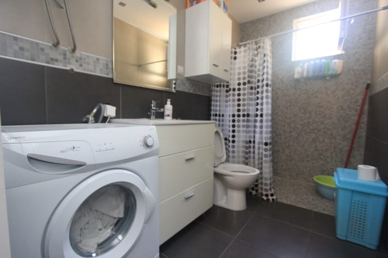 Bathroom in a house, Seoce, Montenegro: washing machine, vanity with sink, shower with curtain, and tiled finish.