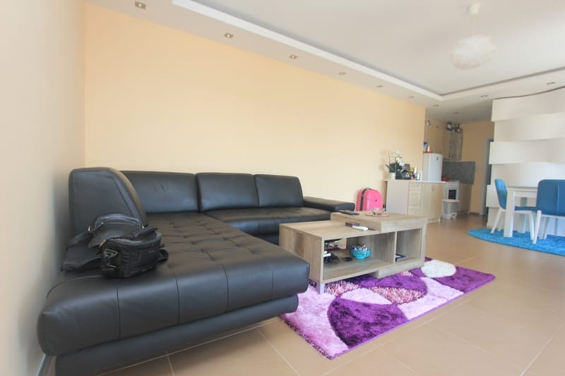 Living room with a black leather sofa and dining area in a house, Seoce, Montenegro. Modern interior with a bright rug.