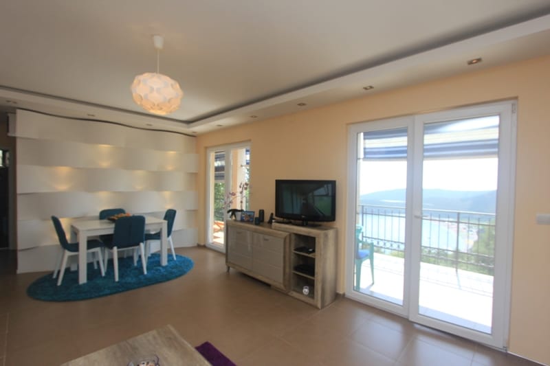 Living room with dining area in a house in Seoce, Montenegro: modern furniture, designer lighting, and sea view.