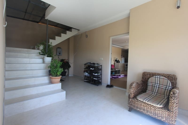 House entryway in Seoc, Montenegro: a bright tiled staircase, a wicker chair, and a view of the living room.