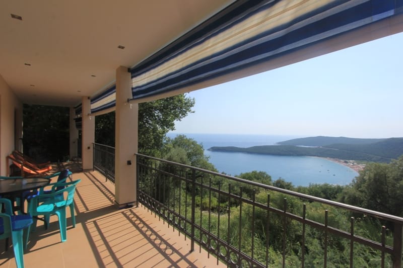 Spacious terrace with sea view in a house, Seoce, Montenegro: plastic furniture, awning, and wrought-iron railing.