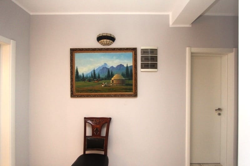 Interior of a house in Uteha, Montenegro: light walls, a landscape painting, a wall sconce, and a classic chair.