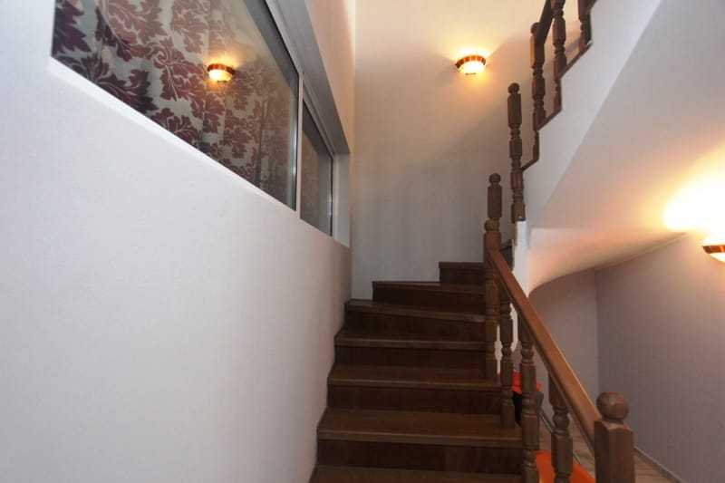 Wooden staircase with carved railings in a house in Uteha, Montenegro, bright interior with wall lights.