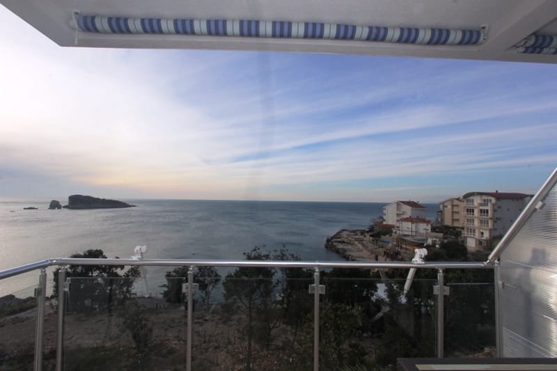 Panoramic sea and island view from the balcony of a house in Utjeha, Montenegro: glass railings and a sunshade.